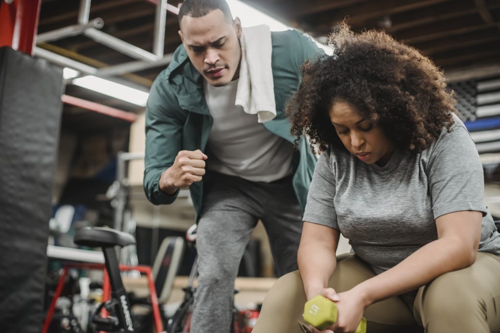 Personal trainer helpt klant met oefening in de sportschool als onderdeel van personal trainer opleiding