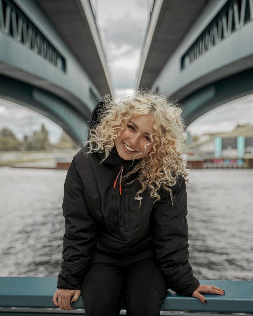 Vrouw met pluizig krullend haar toont hydratatie- en verzorgingstechnieken om pluis te verminderen