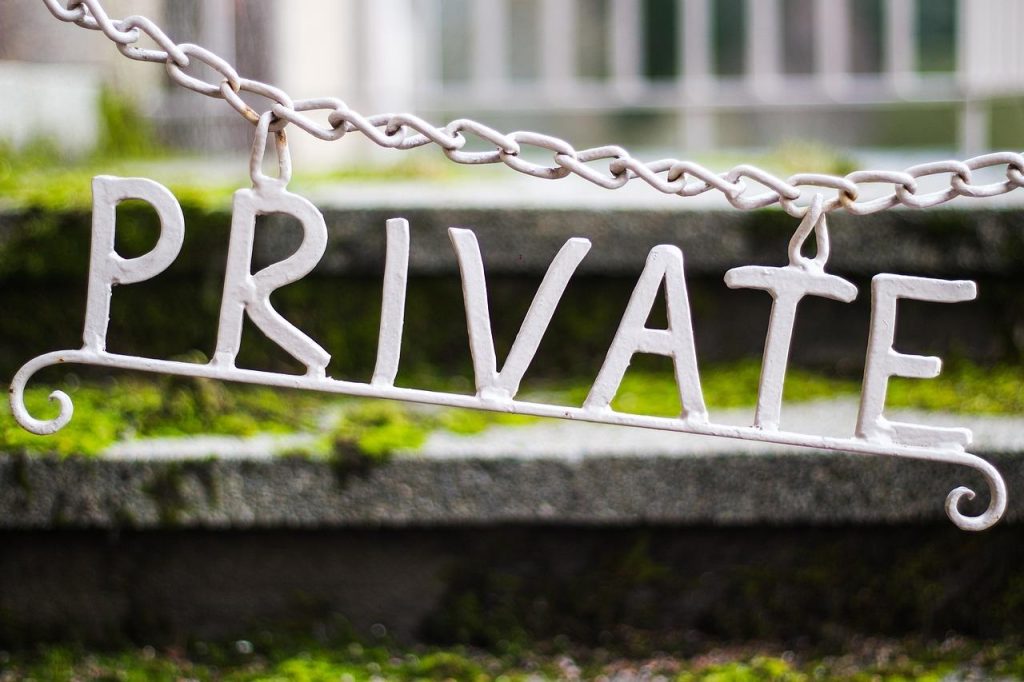 Groene laurierhaag biedt privacybescherming in een achtertuin omringd door moderne tuinelementen