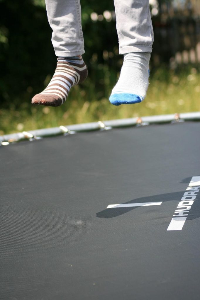 Familie geniet samen van trampolinespringen in de tuin - waarom je een trampoline nodig hebt voor gezondheid en plezier